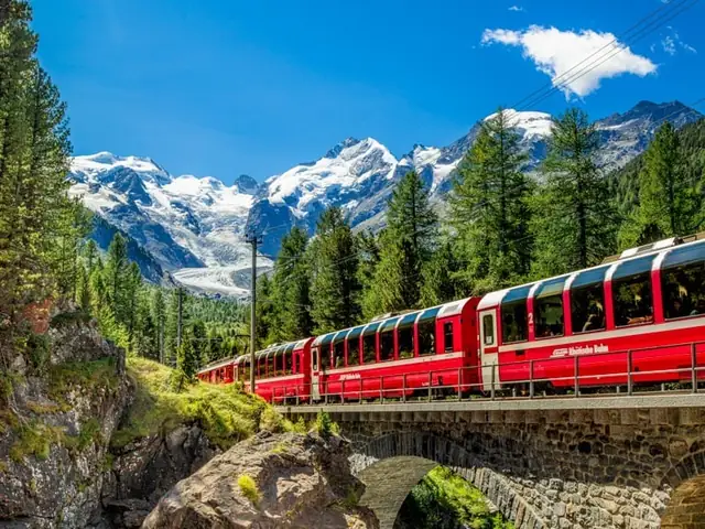 Rode trein over een stenen brug in de Alpen, een treinreis die je boekt bij Vlieg&Trein
